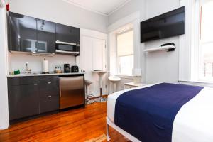 a bedroom with a bed and a kitchen with black cabinets at Charming & Stylish Studio on Beacon Hill #12 in Boston