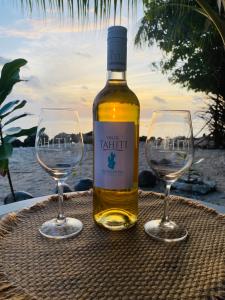 a bottle of wine and two wine glasses on a table at Rangiroa Beach House in Avatoru