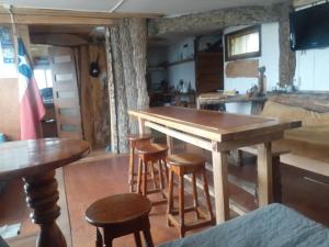 a kitchen with a wooden table and some stools at Refugio Jemmy Button in Puerto Williams