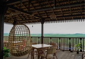 een veranda met een tafel en stoelen en een vogelkooi bij LABIS SUNRISE FARM STAY in Labis