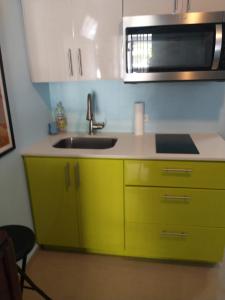 a yellow kitchen with a sink and a microwave at Studio with private entrance and bath near Beach, Unit 4 in San Juan