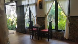 a room with a table and chairs and windows at Doubleyou Homestay Pemuteran in Pemuteran