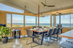 a dining room with a table and chairs and the ocean at Immerse Kangaroo Island in D'Estrees Bay