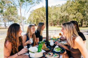 a group of women sitting at a table with food at KangaROOMS Noosa Everglades YHA in Cootharaba