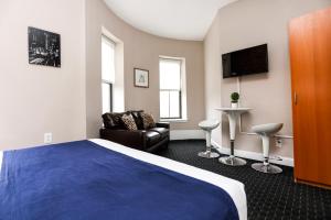 une chambre d'hôtel avec un lit bleu et un canapé dans l'établissement Stylish Studio in Boston Brownstone, C.Ave #21, à Boston