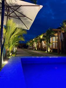 弗烈歇德斯的住宿－Bangalôs Flecheiras de Canaã，夜间在游泳池边的白色遮阳伞