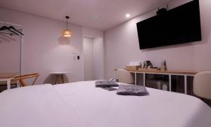a bedroom with a white bed and a flat screen tv at Cheongju Hotel Dictionary in Cheongju