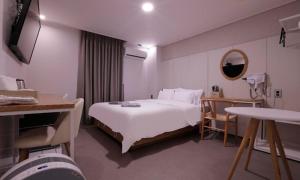 um quarto de hotel com uma cama branca e um espelho em Cheongju Hotel Dictionary em Cheongju