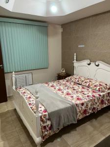 1 dormitorio con cama blanca y manta floral en Casa agradável em frente a praia com jacuzzi/spa, en Niterói