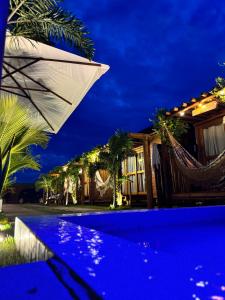 um resort com rede e uma casa à noite em Bangalôs Flecheiras de Canaã em Flecheiras