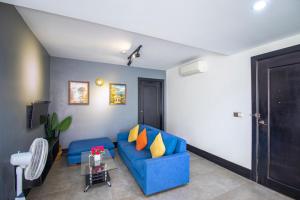 a living room with a blue couch and yellow pillows at 1 BR Serviced Apt In The Heart of Siem Reap in Siem Reap