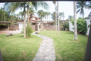 a yard with palm trees and a walk way at Villa Tavares - casa com piscina na praia da Lagoinha in Ubatuba