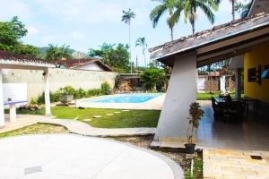 a backyard with a swimming pool and a house at Villa Tavares - casa com piscina na praia da Lagoinha in Ubatuba