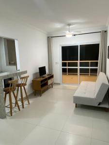 a living room with a couch and a desk with a computer at Apto Ubatuba Praia Tenorio e Praia Grande in Ubatuba