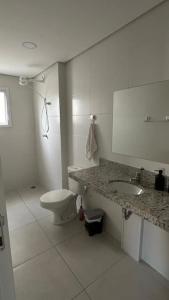 a white bathroom with a toilet and a sink at Apto Ubatuba Praia Tenorio e Praia Grande in Ubatuba