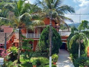 a house with palm trees in front of it at Castelinho do Felix Guarujá Pernambuco in Guarujá