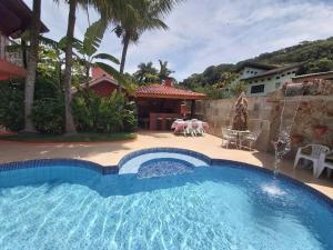 a large swimming pool in a yard with a patio at Castelinho do Felix Guarujá Pernambuco in Guarujá