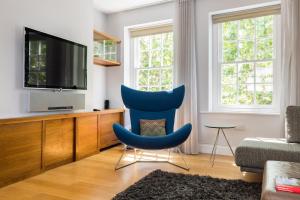 a living room with a tv and a blue chair at London Is Yours - 2 Bedroom in Kensington in London