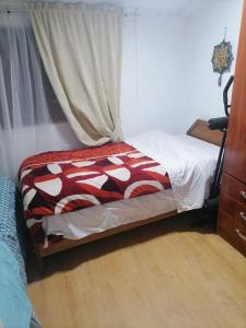 1 dormitorio con 1 cama con manta roja y blanca en Familia Flores Sáez, en Parral
