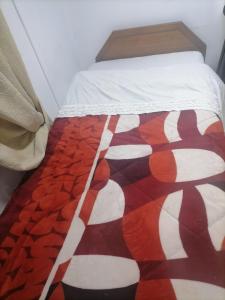 Una cama con una manta roja y blanca. en Familia Flores Sáez, en Parral