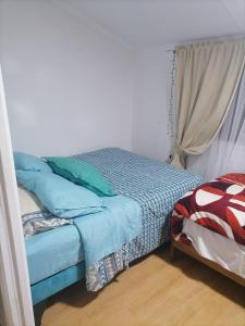 Un dormitorio con una cama con almohadas azules y una ventana en Familia Flores Sáez, en Parral