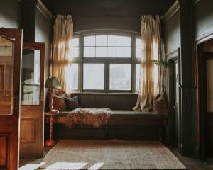 WaratahにあるThe Post Office Waratah - Luxury Wilderness Escapeの窓付きのベッドルーム(ソファ付)