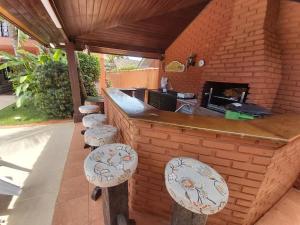 un bar al aire libre con taburetes y una pared de ladrillo en Castelinho do Felix Guarujá Pernambuco en Guarujá