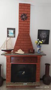 a brick fireplace with a clock on top of it at Castelinho do Felix Guarujá Pernambuco in Guarujá