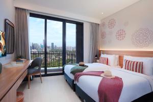 a hotel room with two beds and a desk and a window at Citadines Gatot Subroto Jakarta in Jakarta