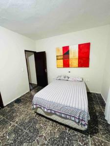 a bedroom with a bed and a painting on the wall at @ Chácara 5 Anjos - Jacuzzi Incrível Água Quente in Itanhaém +45 photos