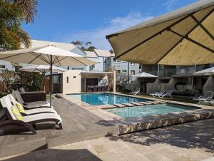 een zwembad met stoelen en parasols naast een gebouw bij Wantima Hastings St 1 Bedroom Unit in Noosa Heads