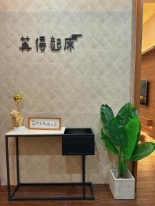 una mesa con una planta junto a una pared con escritura en Ran has to get up en Tainan