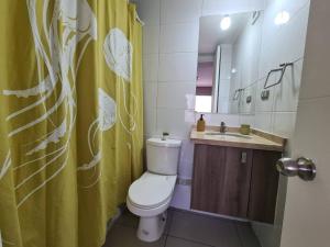 a bathroom with a toilet and a yellow shower curtain at Acogedor Apartamento en Centro de Santiago. in Santiago