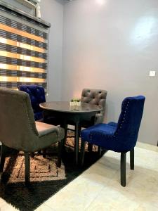 een tafel en stoelen in een kamer met een tafel en blauwe stoelen bij Cozy 3BDR Duplex - Wi-Fi, DSTV, Netflix, Kitchen, Freezer, Exercise Bike, Washing Machine in Agege