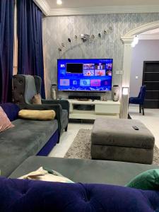 een woonkamer met een grote flatscreen-tv bij Cozy 3BDR Duplex - Wi-Fi, DSTV, Netflix, Kitchen, Freezer, Exercise Bike, Washing Machine in Agege