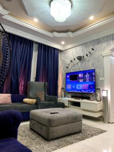 een woonkamer met een televisie, een bank en een stoel bij Cozy 3BDR Duplex - Wi-Fi, DSTV, Netflix, Kitchen, Freezer, Exercise Bike, Washing Machine in Agege