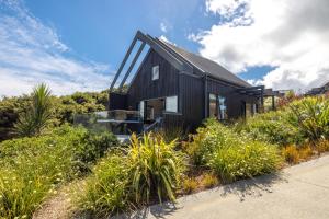 una casa negra en una colina con plantas en The Guest House at Te Whau Retreat en Omiha