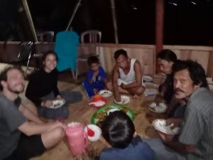 RAMMANG-RAMMANG HOUSE في Maros: مجموعة من الناس جالسين على الأرض يأكلون الطعام