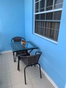 a glass table and two chairs and a blue wall at SK S Haven #1 in Castries