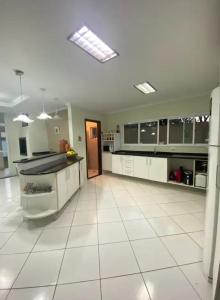 una grande cucina con armadi bianchi e pavimento piastrellato di Sobrado espaçoso em Santa felicidade a Curitiba