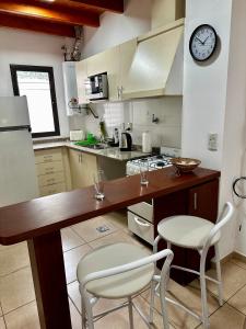 a kitchen with a counter with two chairs and a clock at Sol y Vida in Godoy Cruz