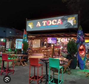 um grupo de cadeiras e mesas em frente a um restaurante de tacos em Maresia 7B em Salvador