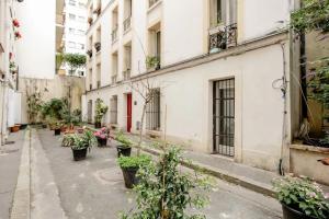 um beco com vasos de plantas e edifícios em La Suite privée des Chevaliers em Paris