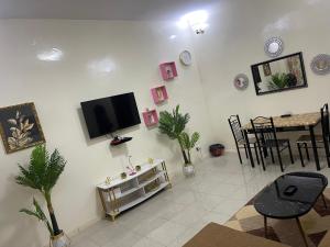 a living room with a tv on the wall and a table at Appartement spacieux a ngor et a proximité des almadies in Ngor