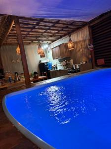 a large blue swimming pool in a room with a kitchen at Bangalôs Flecheiras de Canaã in Flecheiras