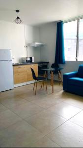 a kitchen with a blue couch and a table and chairs at Little urban idéal pour les séjours de moyenne durée proche de tout in Pointe-à-Pitre