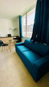 a living room with a blue couch and a table at Little urban idéal pour les séjours de moyenne durée proche de tout in Pointe-à-Pitre