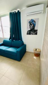 a blue couch in a room with a picture of a woman at Little urban idéal pour les séjours de moyenne durée proche de tout in Pointe-à-Pitre