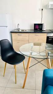a glass table and a black chair in a kitchen at Little urban idéal pour les séjours de moyenne durée proche de tout in Pointe-à-Pitre