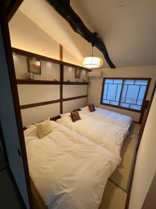 2 łóżka pojedyncze w pokoju z oknem w obiekcie Imakumano Terrace - Dohachi An 道八庵 w mieście Kioto